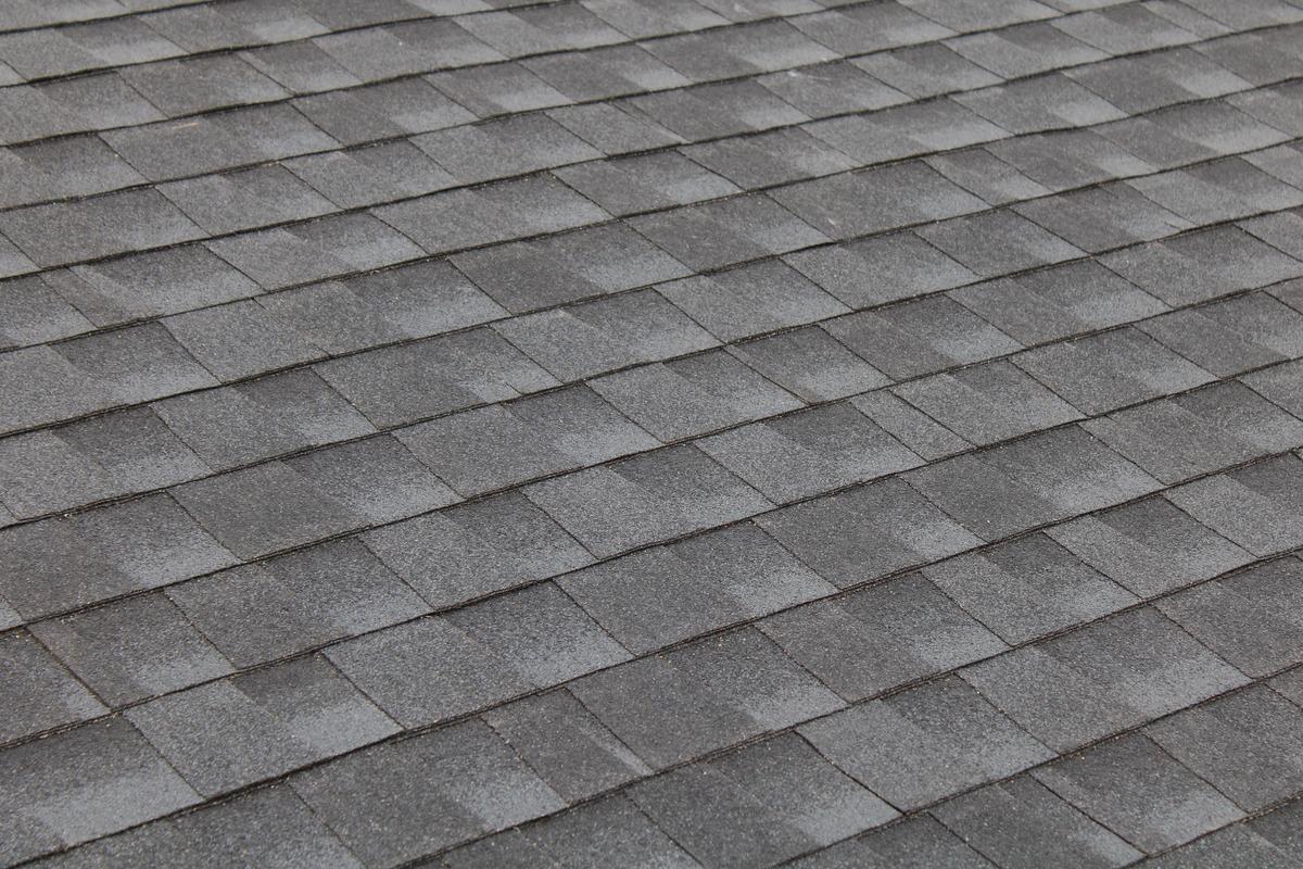 Close-up of gray asphalt shingles being installed